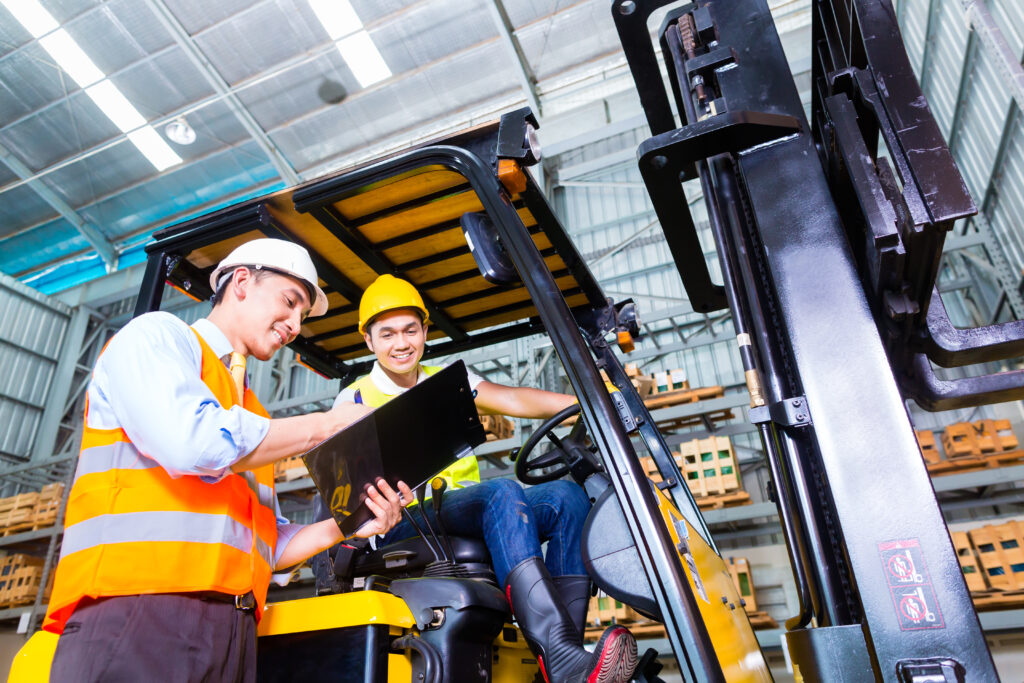 Two men with clipboard on forklift discussing how much does it cost to hire a forklift
