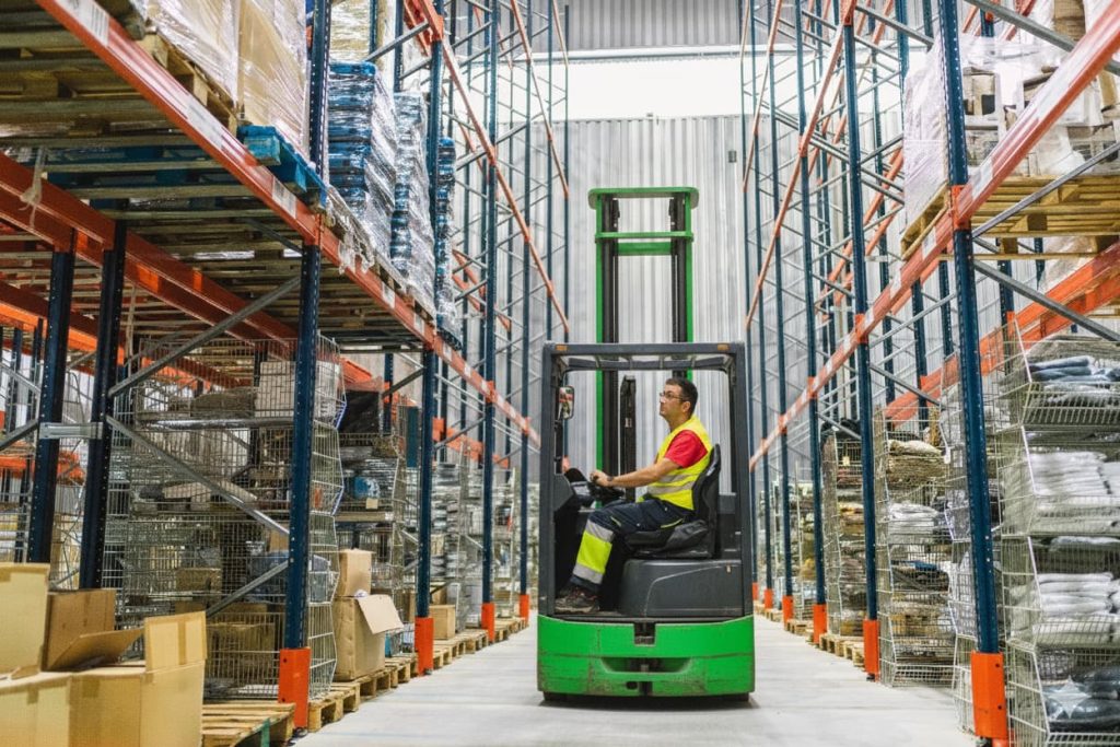 Man in high vis driving multi directional reach forklift