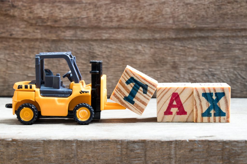 Toy forklift moving blocks that spell out the word Tax