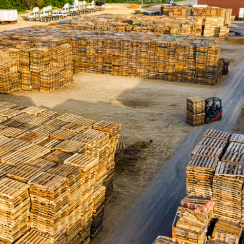 Forklift moving pallets in work yard